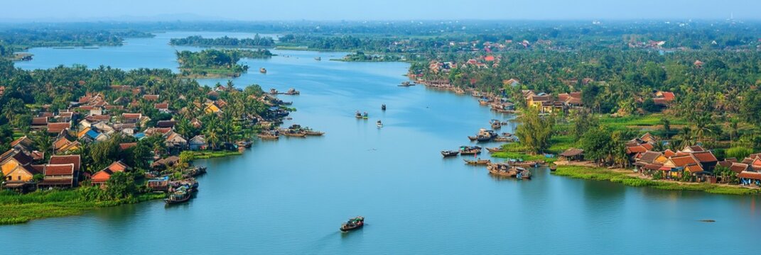 Aerial panoramic view of Thu Bon river with traditional boats and houses in Hoi An, Vietnam