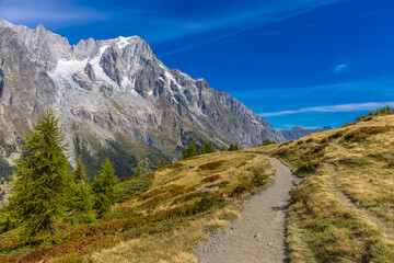 Obraz premium Val Ferret mountain landscape in the Alps. Beautiful alpine scenery of the high mountain summits and green valley in summer under blue sky at sunny weather om Tour du Montblanc