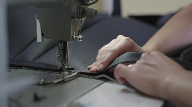 needle with thread sewing machine works workshop. Sewing tailor products from high-quality leather fabric. seamstress sews sewing machine workshop. hands close up. woman seamstress works business