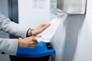 Use of paper towel after washing hands. Close up view of human hands using paper towel after hand...