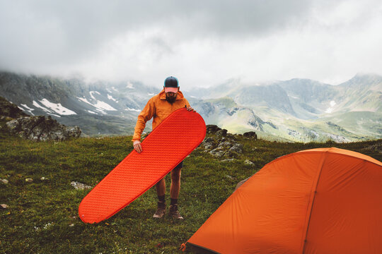 Man mountaineering with camping gear tent and sleeping pad - travel solo adventure healthy lifestyle summer active vacations trip survival climbing equipment