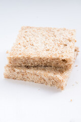 Two slices of whole wheat bread on a white background. The bread has a light brown color and visible texture with small air pockets and bran flecks.