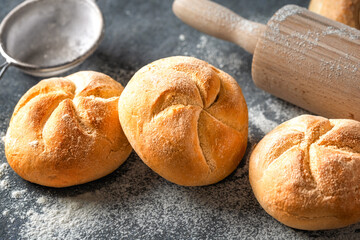Close-up of freshly baked golden bread rolls with a blurred rolling pin in the background. Bakery concept