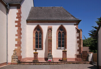 Gothic apse with pointed cinquefoil tracery windows and historical tombstones at the church of Schaidt village, Wörth am Rhein municipality in Germany