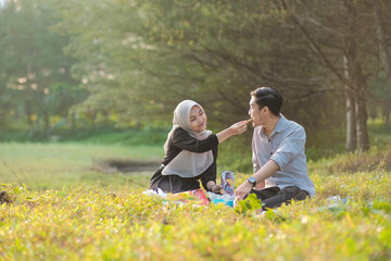 a couple sitting on the park grass while eating snacks