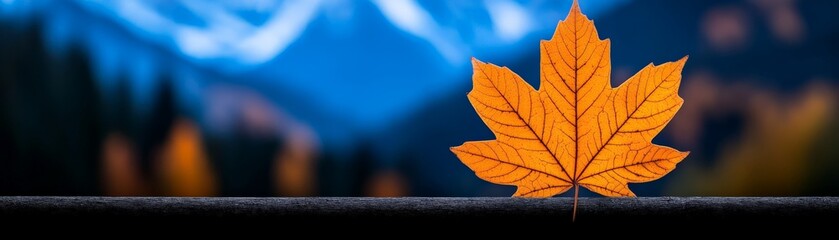 Obraz premium Autumn's Embrace: A single, vibrant orange maple leaf rests delicately on a branch, its intricate details accentuated against a backdrop of blurred mountains and forest.