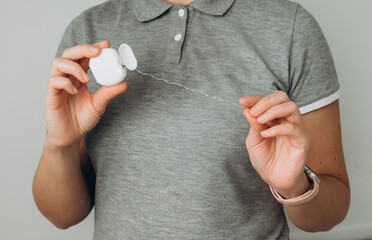 Person using dental floss for oral hygiene in a well-lit indoor setting