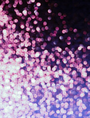 A bokeh effect photograph, out of focus lights creating a pink and purple circles texture background
