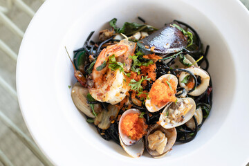 Squid ink spaghetti with garlic, olive oil, chili and seafood on white dish.