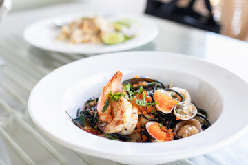 Squid ink spaghetti with garlic, olive oil, chili and seafood on white dish.