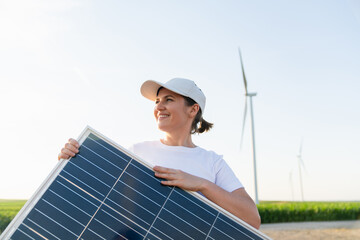 Woman wearing white cap and t-shirt holds solar panel