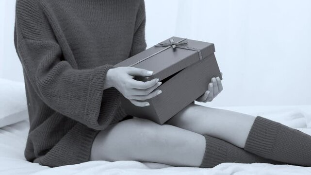 The girl opens the gift box and takes out a present. Woman holding adult toys in hand on a white background in bedroom.