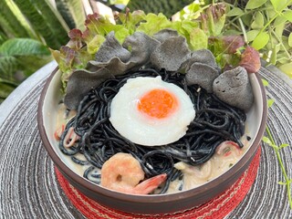 Stir-fried black spaghetti with shrimp cream sauce and soft eggs and black Rice Cracker