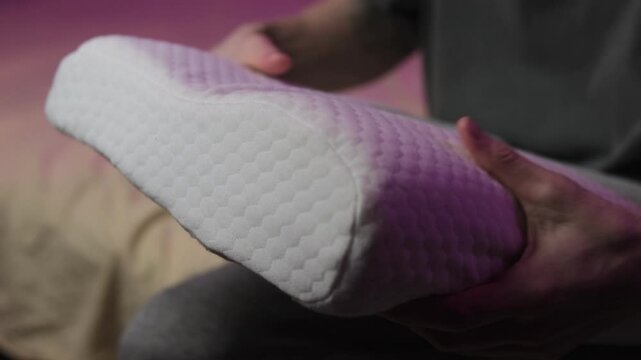 Male patient sitting and examining orthopedic pillow recommended by doctor