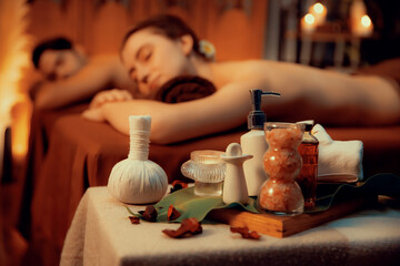 Aromatherapy massage ambiance or spa salon composition setup with focus decor candles and spa accessories on blur couple enjoying blissful aroma spa massage in resort or hotel background. Quiescent