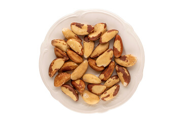 Brazil nuts without shells on a white ceramic plate on a white background, close-up, top view.