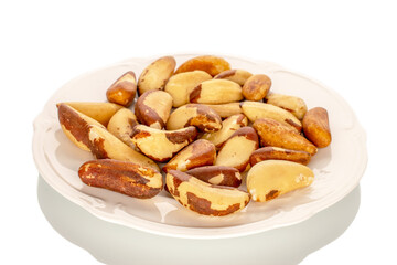 Brazil nuts without shells on a white ceramic plate, close-up, isolated on a white background.