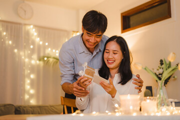 diner, valentine, romantic, anniversary, communicate, community, loving, love, hugging, affection. A man and woman are opening a gift together, as the couple shares a special moment together.