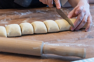 Woman preparing traditional cinnamon rolls in kitchen