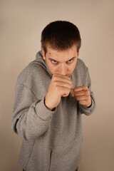 The mood is dynamic and intense. Wearing a sports hoodie, the man stands with fists clenched,...