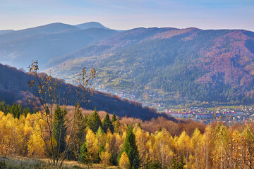 Aerial view of an autumn village in a valley and mountains in a blue haze