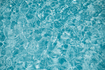 crystal clear blue water surface in swimming pool or ocean with ripples and sunlight reflection background