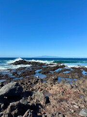 The view of the blue ocean waves and volcanic rocks on the coast of Palm-Mar, sunny winter day in Malpaís de La Rasca natural resort, Tenerife, Canary Islands, Spain