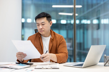Serious man behind paperwork, mature financier checking investment contracts and reports....