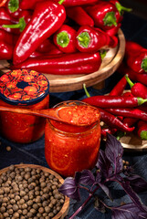 Jars of spicy red pepper sauce with fresh ingredients