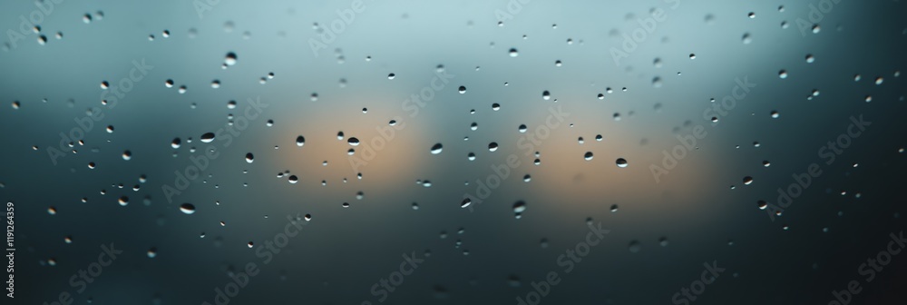 Poster Sparkling raindrops clinging to a glass surface, creating a mesmerizing pattern against a backdrop of soft, blurred lights, evoking a sense of tranquility and peace during a rainy day