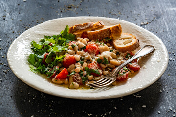 White beans with cherry tomatoes, parmesan, lemon and garlic on black table