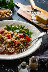 White beans with cherry tomatoes, parmesan, lemon and garlic on black table