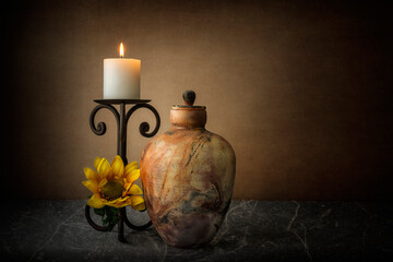 Fine art 1:1 ratio color image of a fired urn with a candle and candle holder along with silk sunflower