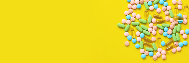 Vitamins of different colors on a yellow background. Top view of a bunch of bright pills. Pharmaceutical industry. Health care and medicine. Pharmacy product. Banner, copy space