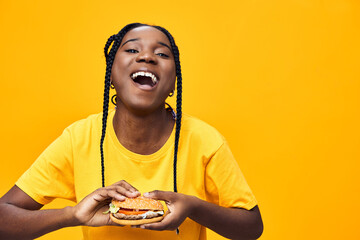 Happy girl holding a colorful sandwich against a vibrant yellow background, showcasing joy, healthy...