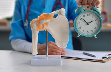 Doctor skeleton shoulder joint and muscles with alarm clock