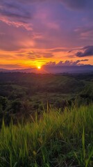 Obraz premium A vibrant sunset over lush green hills and valleys.