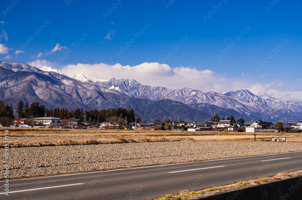 Wall mural 冬の冠雪した北アルプスと道路