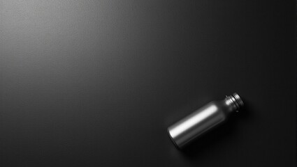 Minimalist black workout mat with gleaming steel water bottle bathed in soft light
