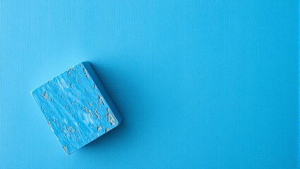 Top view of textured blue yoga mat with a foam block in bottom left corner showing signs of use