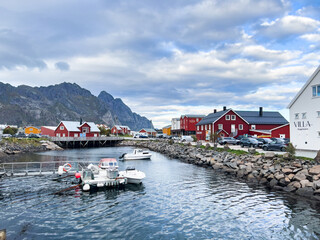 Naklejka premium A scenic view of Henningsvær in Lofoten Islands, northern Norway, showcasing traditional buildings along the harbor with mountains in the background.