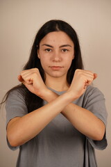 The gesture shows determination and resolve. A woman crosses her arms in front of her, fists clenched, signaling readiness for protection. Her posture conveys a sense of defense and strength.