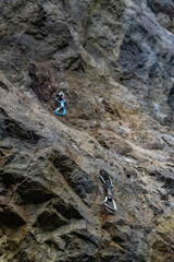 climbing equipment on a rock wall. blue and black quickdraw hanging on a sport climbing route 