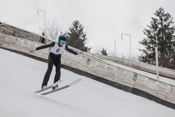 Jumper soaring through the air and landing gracefully on the snow during hill ski jumping practice. Extreme winter sports concepts. © 24K-Production