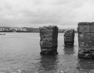 This captivating photo showcases the weathered, rustic bridge pillars standing proudly in the calm waters of Sos&uacute;a Bay, Dominican Republic. The crumbling structure adds a sense of history and mystery 