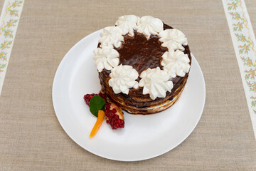 Delicious layered cake decorated with whipped cream and fruit on a white plate