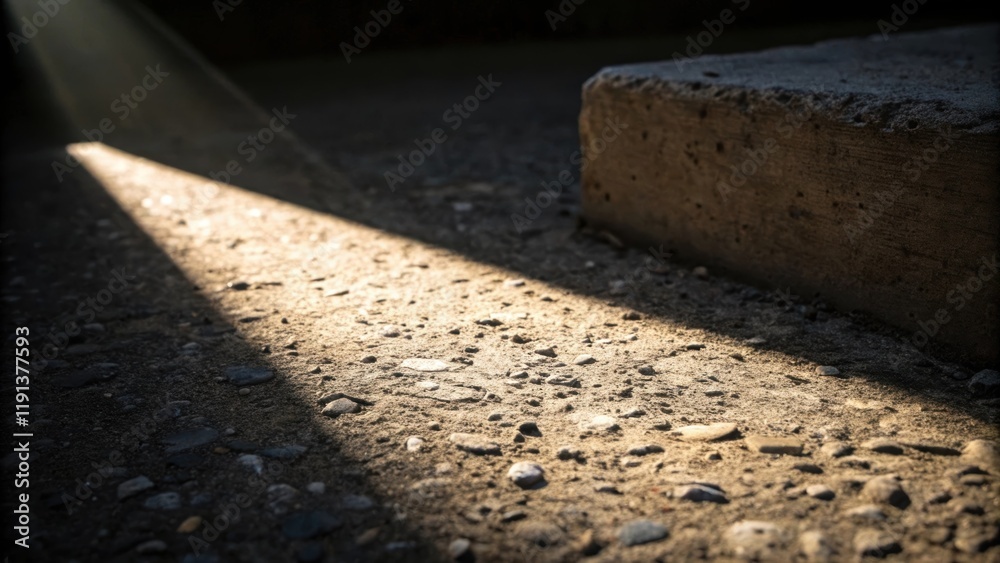 Aufkleber A closeup captures the interplay of light and shadow over a rough concrete patch where a single beam of light interacts with a protruding piece of aggregate creating a vivid