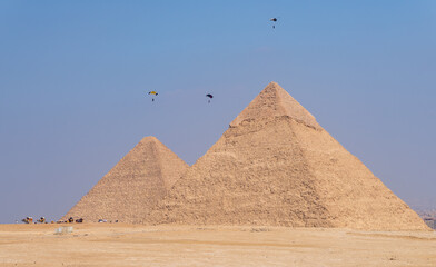 Hang gliders flying down to land beside the pyramid of Khafre and Great Pyramid of Giza