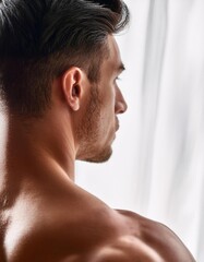 Naklejka premium Extreme closeup of shoulder of a beautiful athletic man, back view, blurred white curtain background, natural light