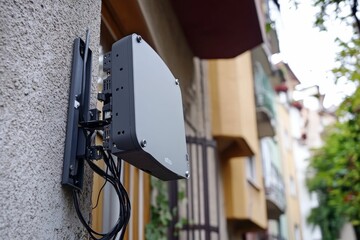 Gray device mounted on wall, exterior wires visible.